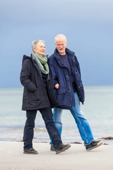 older adult happy couple walks on the beach in autumn lifestyle happiness