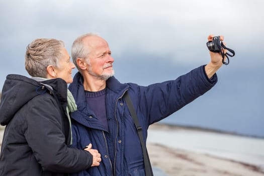 older adult couple seniors happy to take self-portrait photograph with digital camera on vacation