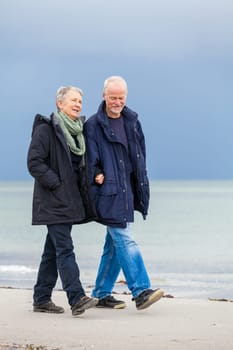 older adult happy couple walks on the beach in autumn lifestyle happiness