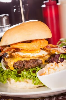 Delicious hamburger cheeseburger with bacon egg and salad on a plate