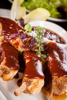 Grilled pork ribs Spareribs with barbecue sauce marinade and herb salad on a plate