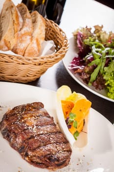 Succulent grilled beef fillet steak with homemade herb butter on a plate isolated against a white background