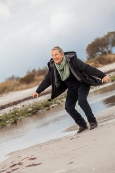 happy active older woman pensioner senior in the open at the sea in autumn