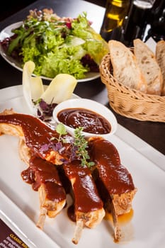 Grilled pork ribs Spareribs with barbecue sauce marinade and herb salad on a plate