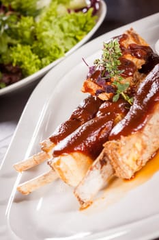 Grilled pork ribs Spareribs with barbecue sauce marinade and herb salad on a plate