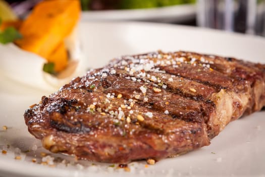 Succulent grilled beef fillet steak with homemade herb butter on a plate isolated against a white background