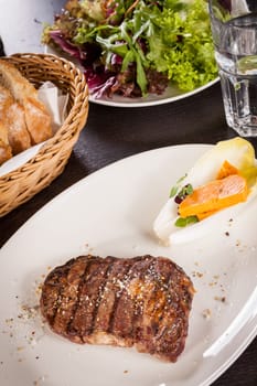 Succulent grilled beef fillet steak with homemade herb butter on a plate isolated against a white background