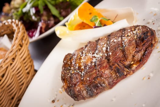 Succulent grilled beef fillet steak with homemade herb butter on a plate isolated against a white background