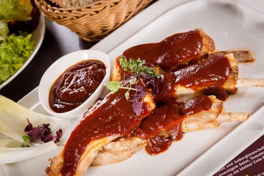 Grilled pork ribs Spareribs with barbecue sauce marinade and herb salad on a plate