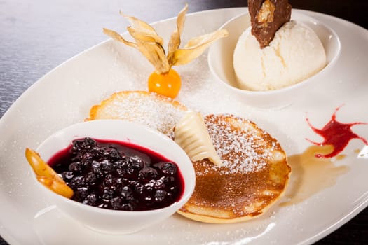 Delicious sweet pancakes as desser with vanilla ice cream prepared on a white plate
