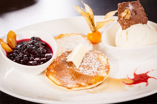 Delicious sweet pancakes as desser with vanilla ice cream prepared on a white plate
