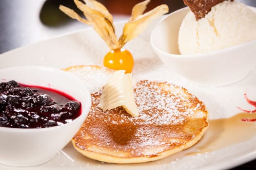 Delicious sweet pancakes as desser with vanilla ice cream prepared on a white plate