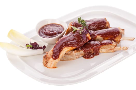 Grilled pork ribs Spareribs with barbecue sauce marinade and herb salad on a plate isolated against a white background