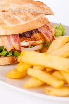 Club sandwich on toasted white bread with bacon and fries fried fries on a plate isolated against a white background