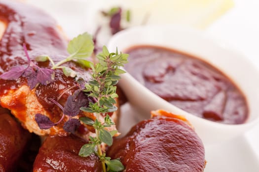 Grilled pork ribs Spareribs with barbecue sauce marinade and herb salad on a plate isolated against a white background