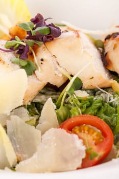 Fresh delicious caesarsalat with grilled chicken bust parmesan shards and croutons isolated against a white background