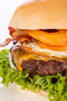 Delicious hamburger cheeseburger with bacon egg and salad on a plate isolated on a white background