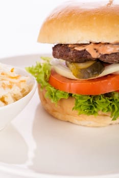 Delicious hamburger cheeseburger with bacon egg and salad on a plate isolated on a white background