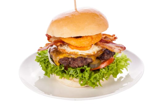 Delicious hamburger cheeseburger with bacon egg and salad on a plate isolated on a white background