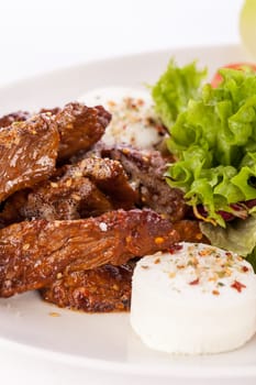 Fresh salad with fresh goat cheese and fried beef strips prepared on a plate insulated against a white background
