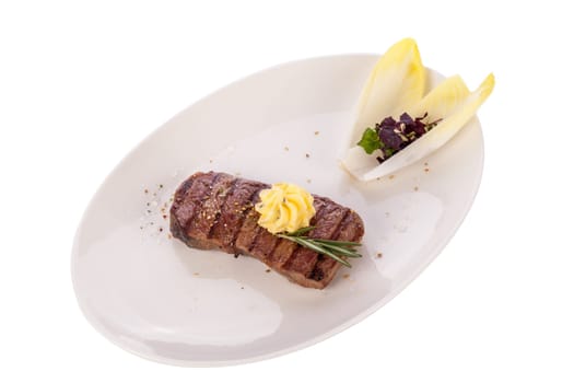 Succulent grilled beef fillet steak with homemade herb butter on a plate isolated against a white background