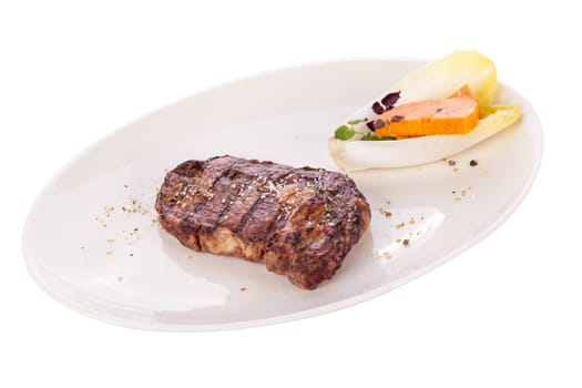 Succulent grilled beef fillet steak with homemade herb butter on a plate isolated against a white background
