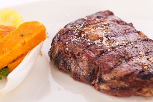 Succulent grilled beef fillet steak with homemade herb butter on a plate isolated against a white background