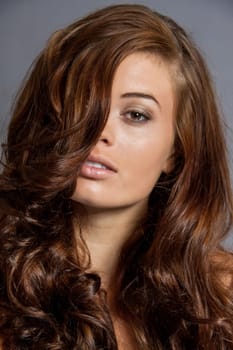 Young attractive brunette woman with curls and white top as portrait