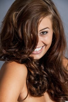 Young attractive brunette woman with curls and white top as portrait