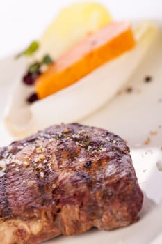 Succulent grilled beef fillet steak with homemade herb butter on a plate isolated against a white background