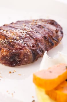 Succulent grilled beef fillet steak with homemade herb butter on a plate isolated against a white background