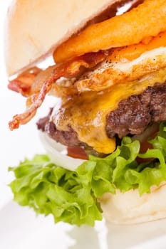 Delicious hamburger cheeseburger with bacon egg and salad on a plate isolated on a white background