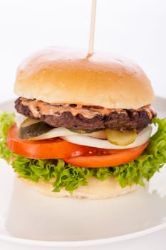 Delicious hamburger cheeseburger with bacon egg and salad on a plate isolated on a white background