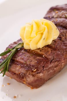 Succulent grilled beef fillet steak with homemade herb butter on a plate isolated against a white background