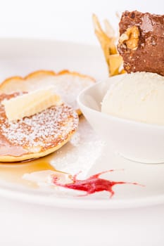 Delicious sweet pancakes as desser with vanilla ice cream prepared on a white plate insulated against a white background