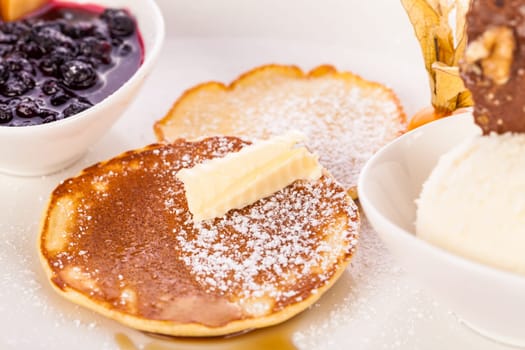Delicious sweet pancakes as desser with vanilla ice cream prepared on a white plate insulated against a white background