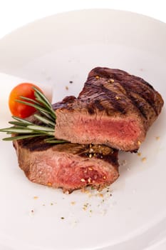Medium fried beef steak fillet with pepper and rosemary sliced on a plate insulated against white background