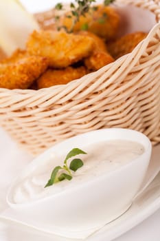 Fresh chicken flails and nuggets golden fried in a basket insulated against a white background