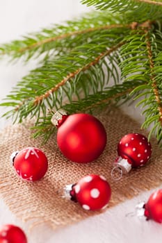 Beautiful red Christmas balls with small white dots with green fir branches on a jute sack