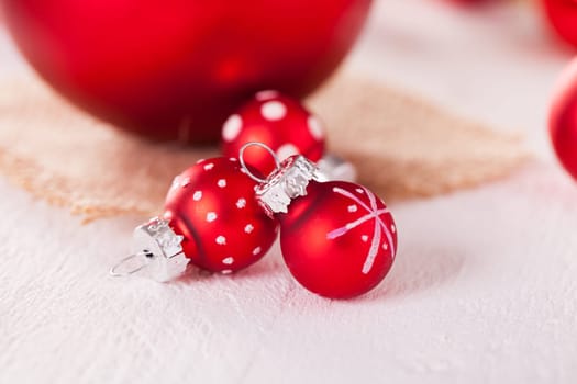 large and small red Christmas tree balls on a wooden board with a jutesack as a close-up