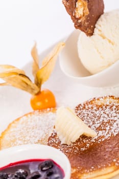 Delicious sweet pancakes as desser with vanilla ice cream prepared on a white plate insulated against a white background