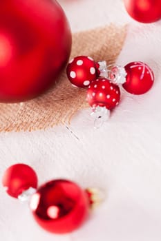 large and small red Christmas tree balls on a wooden board with a jutesack as a close-up