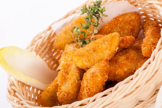 Fresh chicken flails and nuggets golden fried in a basket insulated against a white background