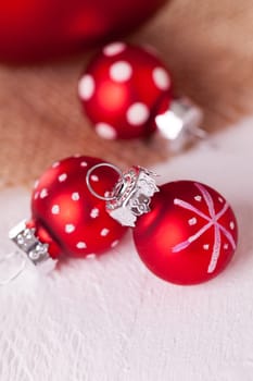 large and small red Christmas tree balls on a wooden board with a jutesack as a close-up