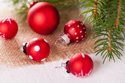 Beautiful red Christmas balls with small white dots with green fir branches on a jute sack