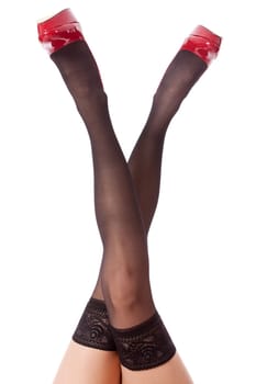 Sexy long legs of an attractive woman with black stockings and red stilettos isolated against a white background