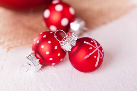large and small red Christmas tree balls on a wooden board with a jutesack as a close-up