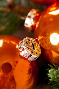 Shiny orange glass balls Christmas balls with green twigs on a jute sack as a close-up