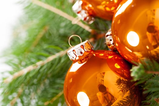 Shiny orange glass balls Christmas balls with green twigs on a jute sack as a close-up