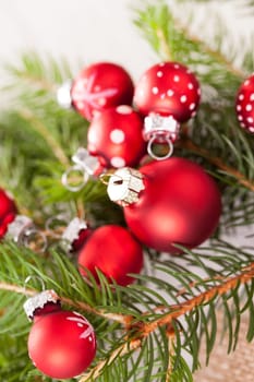 Beautiful red Christmas balls with small white dots with green fir branches on a jute sack